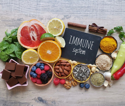 Immune system chalkboard sign surrounded by fresh fruit, vegetables, nuts and spices — daily multivitamin and omega-3 support immune health