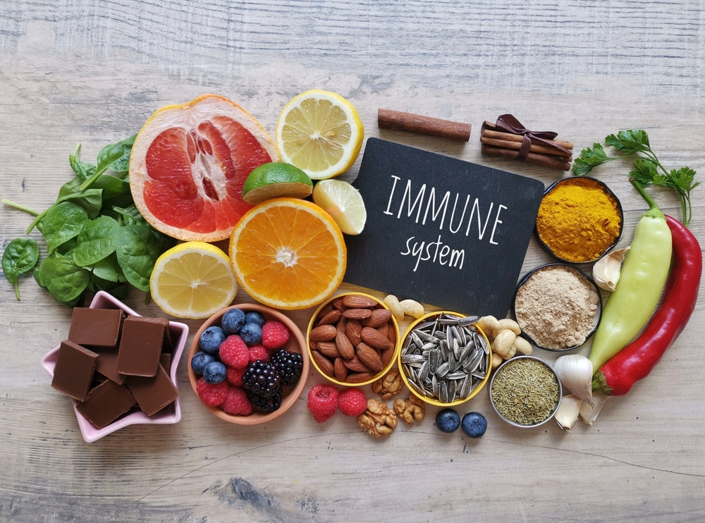 Immune system chalkboard sign surrounded by fresh fruit, vegetables, nuts and spices — daily multivitamin and omega-3 support immune health