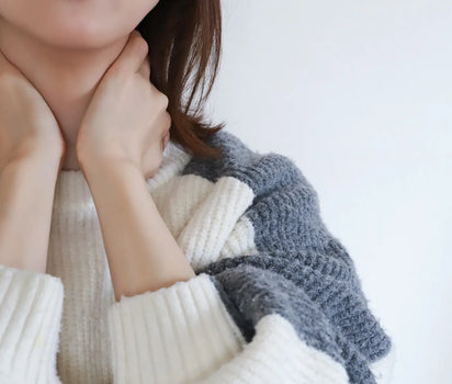 Woman holding her stiff neck with both hands in cream knit jumper — glucosamine and collagen support cartilage health and mobility