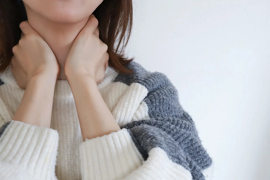 Woman holding her stiff neck with both hands in cream knit jumper — glucosamine and collagen support cartilage health and mobility