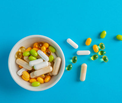 Bowl of mixed vitamin capsules and tablets on blue background — daily multivitamin supports energy and overall health
