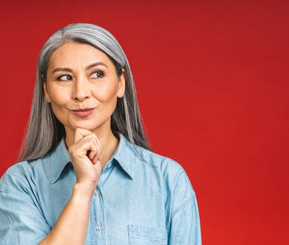 Magnesium supports menopause symptoms, sleep and mood — mature woman with grey hair on red background