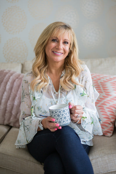 Woman sitting on a couch holding a mug .