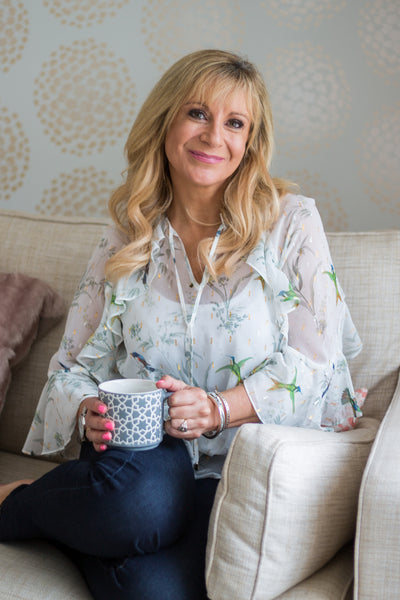 Woman sitting on a couch holding a mug in a home setting